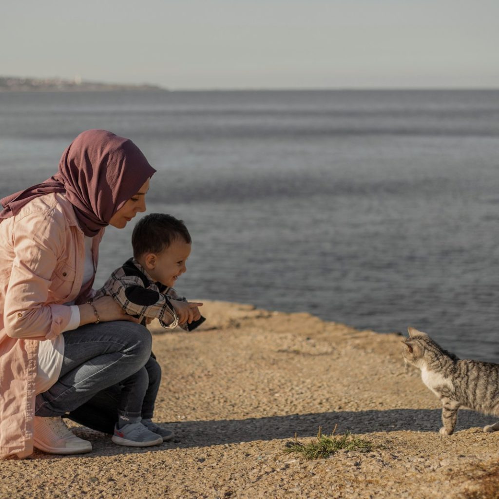 a person and a child looking at a fox on a beach