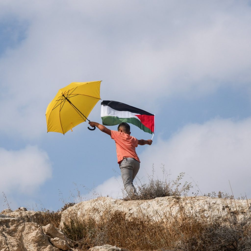 a children holding a flag and a yellow umbrella