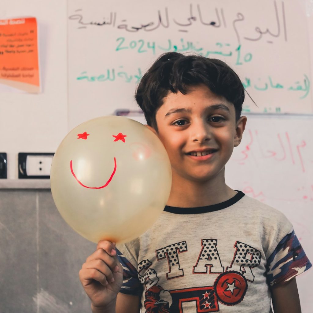 A young boy holding a balloon with a smiley face on it